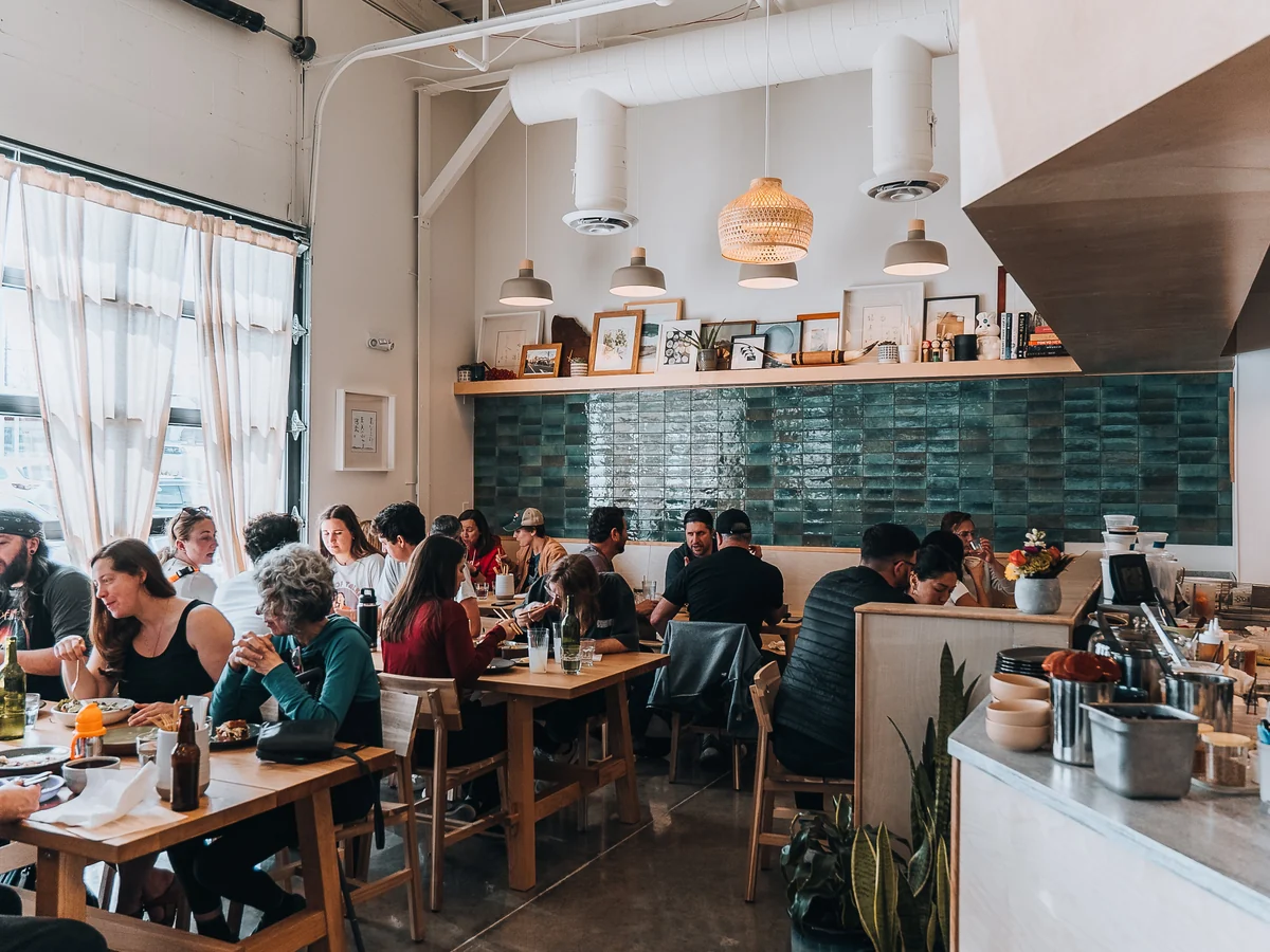 Guests dine in Kisser’s bright dining room beside a teal tiled wall.